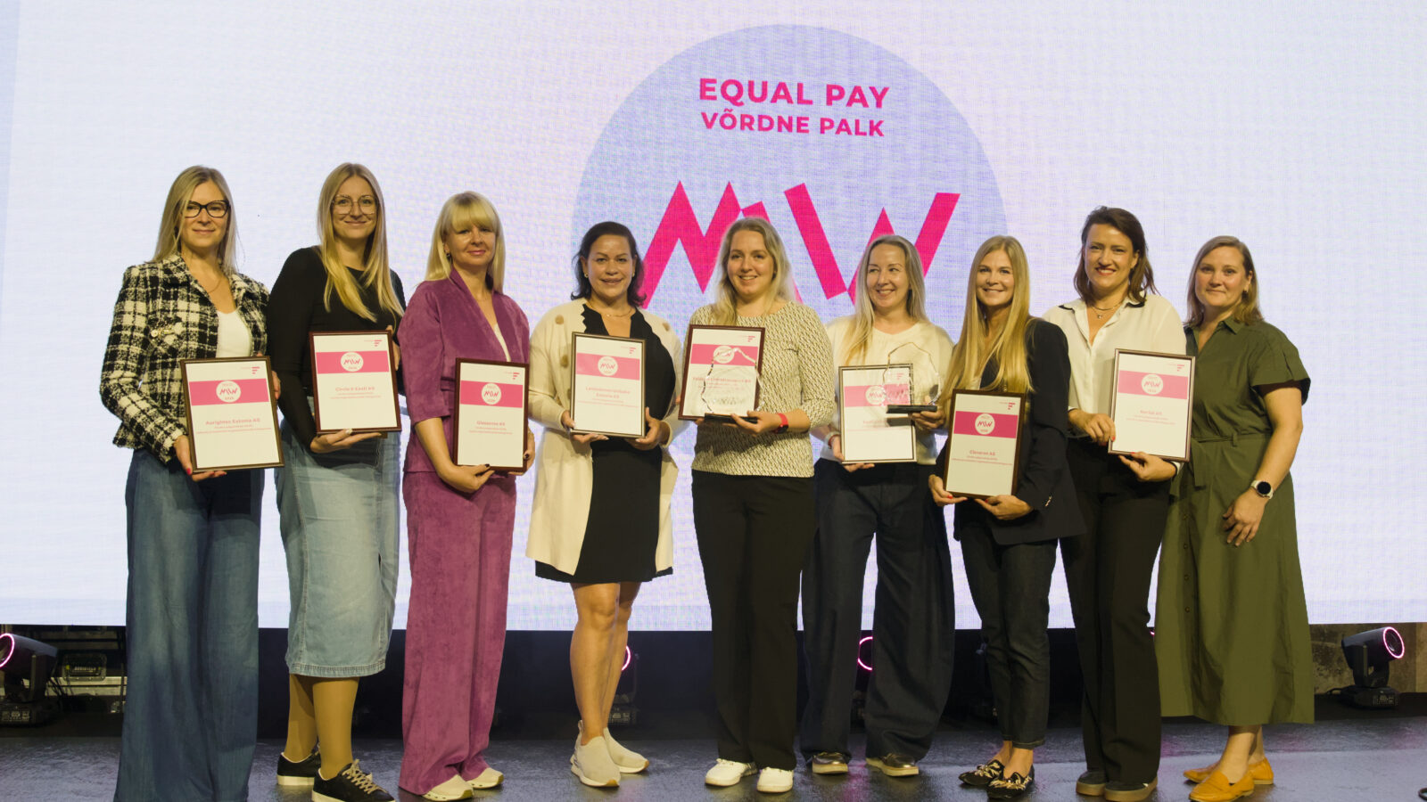 Equal Pay / Võrdne palk tunnustusüritusel laval seisavad ettevõtete esindajad tunnistustega, nende seas Cleveroni esindaja
